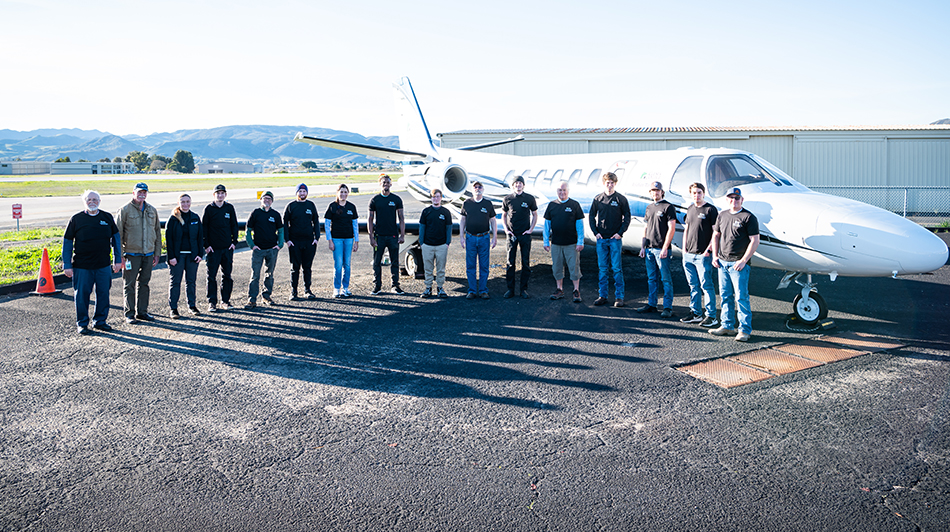 Group of aviation students in front of plane.