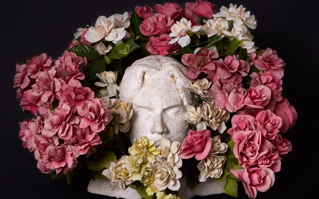 White statue with flowers around it.